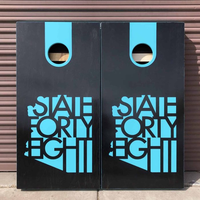 State Forty Eight Black and Turquoise cornhole board with garage background